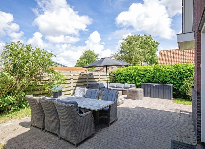 Zijaanzicht van Villa Magnifique, een vakantiehuis in Den Burg Texel, omgeven door groen.