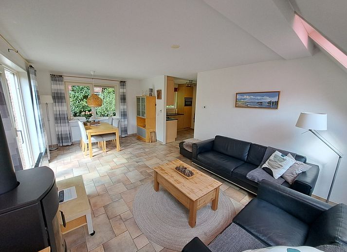 Koperwiek vakantiehuis met houten veranda in Den Burg, Texel, omgeven door groen.