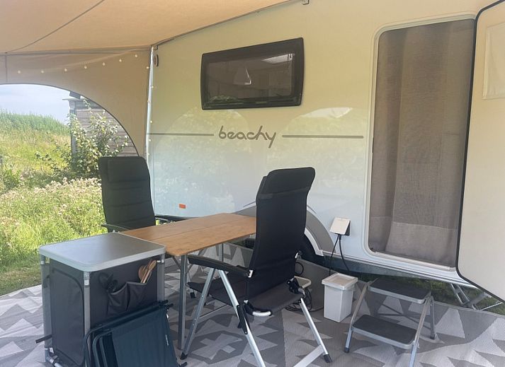 Caravan Beachy Don Voorzorg in Den Burg, Texel met zonnige veranda en groene omgeving.