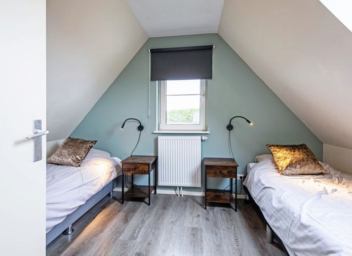 Gezellige woonkamer van Vakantiehuisje in Den Burg, Texel met comfortabele zithoek en uitzicht op de tuin, ideaal voor ontspanning.