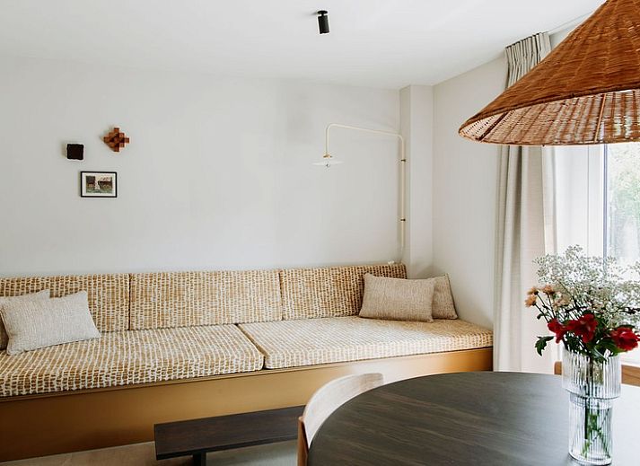 Gemuetliche Sitzecke im Luxury Apartment 4p, Den Burg, Texel mit stilvoller Rattanlampe und frischen Blumen.