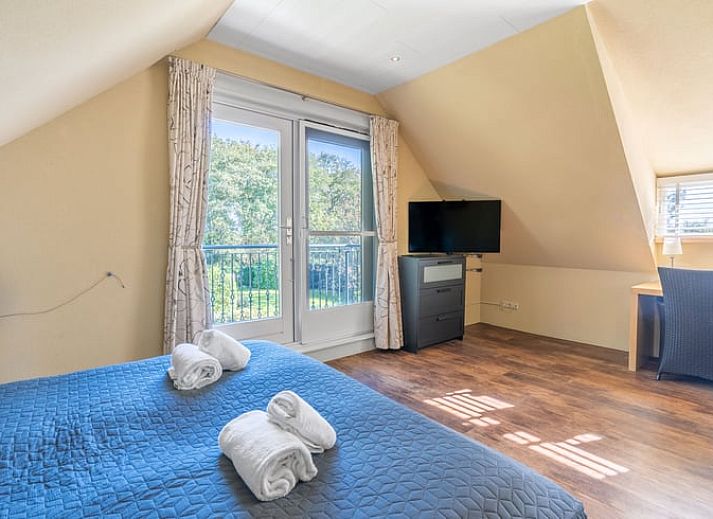 Ruime zitkamer in Huisje in Den Burg, Texel met grote ramen en veel natuurlijk licht.