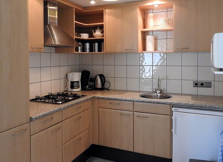 Gemuetlicher Garten im Bungalow der Familie Smit in Den Burg, Texel, mit bunten Blumen und gruenen Hecken.