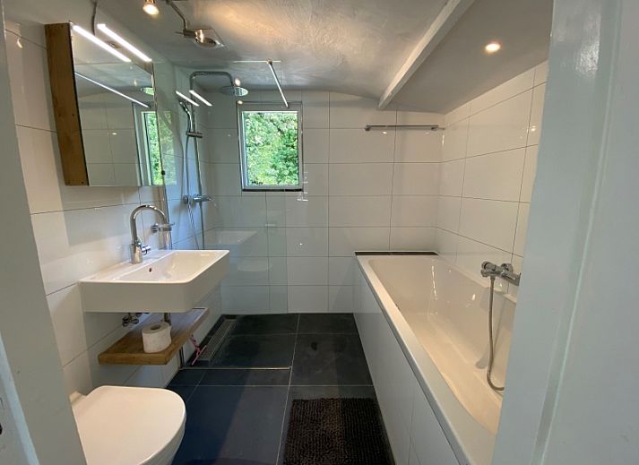 Gezellige woonkamer van Kogerstraat 98A in Den Burg, Texel, met houten meubels en een ruime zithoek.