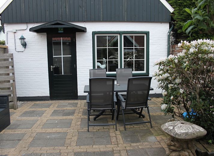 Spacious terrace at De Molen, vacation home in Den Burg, Texel, with garden furniture and flowers.