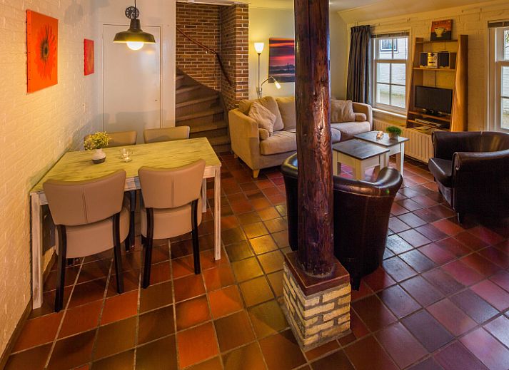 Charmante ingang van Appartement De Kwikstaart in Den Burg, Texel, omgeven door weelderige natuur en rustieke stenen muren.