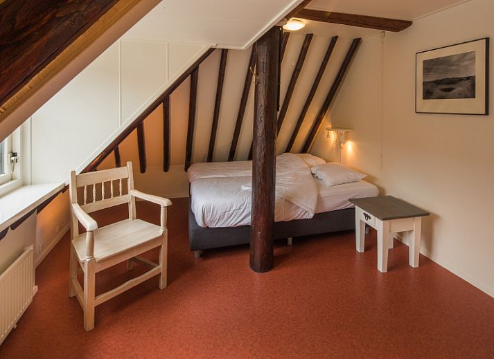 Charmante ingang van Appartement De Kwikstaart in Den Burg, Texel, omgeven door weelderige natuur en rustieke stenen muren.