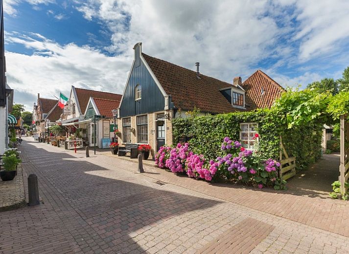 Charmante ingang van Appartement De Kwikstaart in Den Burg, Texel, omgeven door weelderige natuur en rustieke stenen muren.