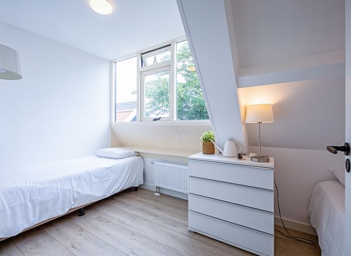 Modernes Wohnzimmer im Hotel Loodsmans Welvaren - Apartment, Den Hoorn, Texel mit geraeumiger Sitzecke und Esstisch aus Holz.