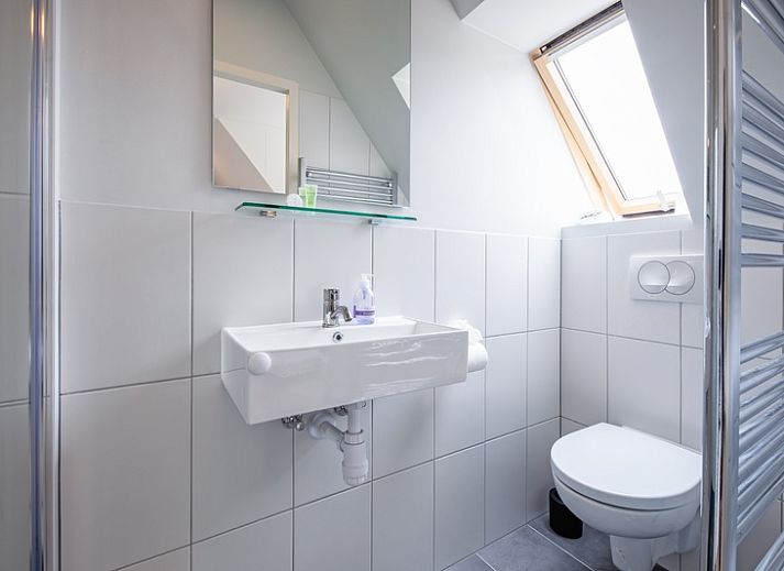 Modernes Wohnzimmer im Hotel Loodsmans Welvaren - Apartment, Den Hoorn, Texel mit geraeumiger Sitzecke und Esstisch aus Holz.