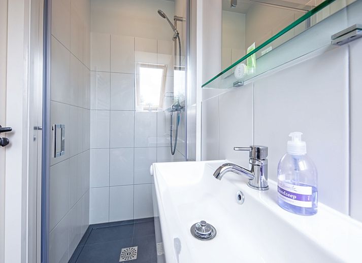 Modernes Wohnzimmer im Hotel Loodsmans Welvaren - Apartment, Den Hoorn, Texel mit geraeumiger Sitzecke und Esstisch aus Holz.