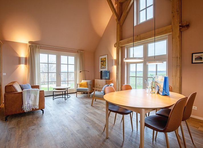 Gemuetliches Wohnzimmer im Ferienhaus Kamille in Den Hoorn auf Texel mit komfortabler Sitzecke und Blick auf die gruene Umgebung.