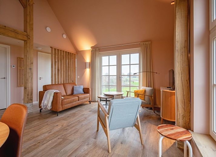 Gemuetliches Wohnzimmer im Ferienhaus Kamille in Den Hoorn auf Texel mit komfortabler Sitzecke und Blick auf die gruene Umgebung.