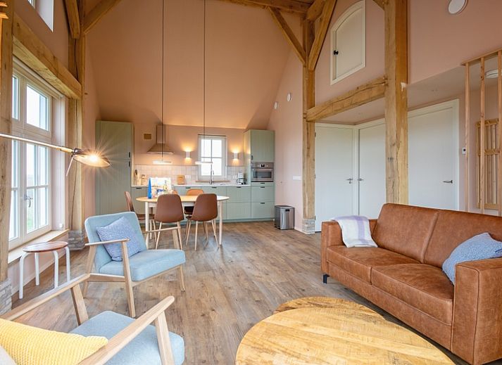 Gemuetliches Wohnzimmer im Ferienhaus Kamille in Den Hoorn auf Texel mit Holzinterieur und Blick auf die Natur der Watteninseln.