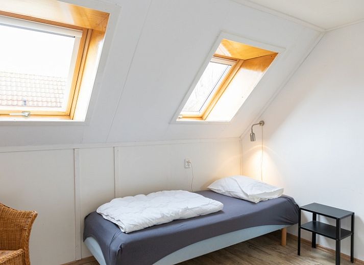 Charmante buitenkant van Arendsnest vakantiehuis in Den Hoorn Texel, omgeven door groene natuur en bloeiende planten.