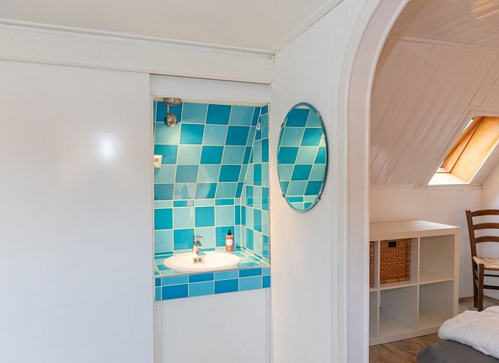 Charmante buitenkant van Arendsnest vakantiehuis in Den Hoorn Texel, omgeven door groene natuur en bloeiende planten.