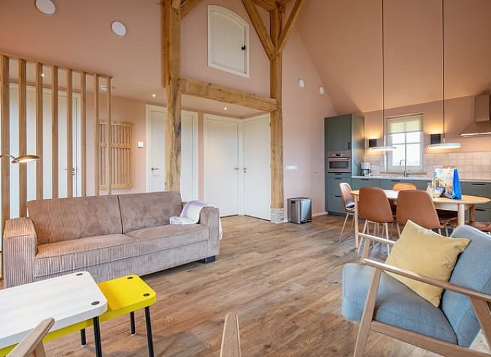 Gezellige woonkamer in het Huisje in Den Hoorn, Texel met houten balken en veel lichtinval, ideaal vakantiehuis op de Waddeneilanden.