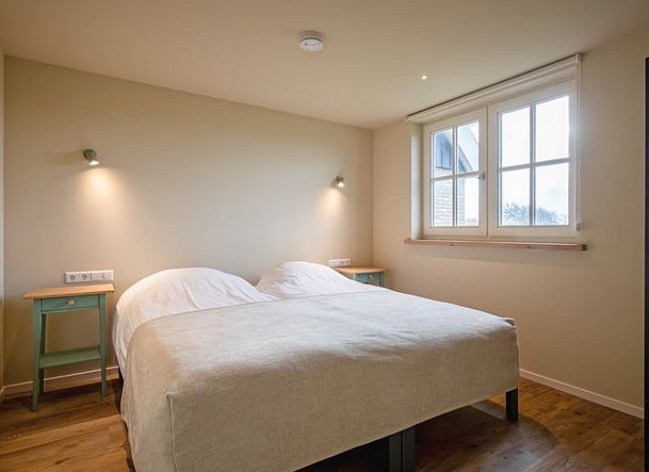 Gezellige woonkamer in het Huisje in Den Hoorn, Texel met houten balken en veel lichtinval, ideaal vakantiehuis op de Waddeneilanden.