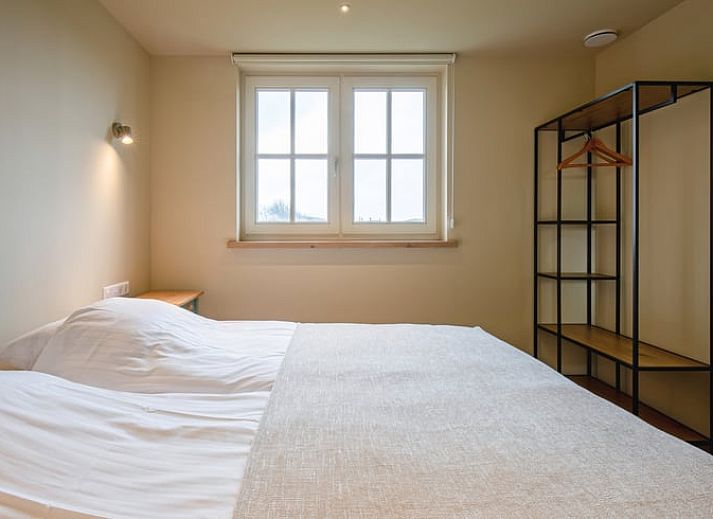 Gezellige woonkamer in het Huisje in Den Hoorn, Texel met houten balken en veel lichtinval, ideaal vakantiehuis op de Waddeneilanden.