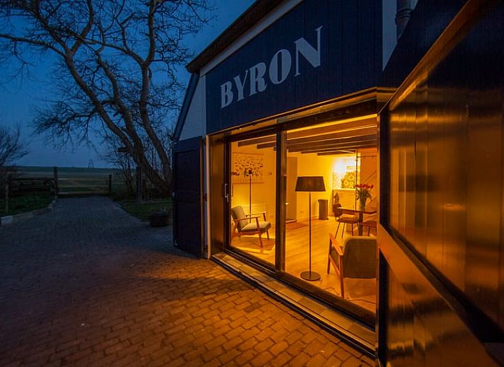 Holzschild mit der Aufschrift "Gaestehaus" an einem Ferienhaus in Oosterend, Texel, umgeben von Gruenanlagen.