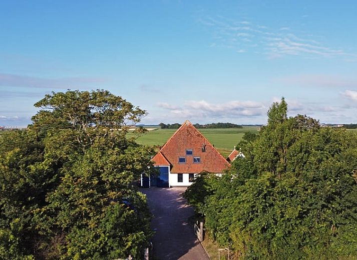 Holzschild mit der Aufschrift "Gaestehaus" an einem Ferienhaus in Oosterend, Texel, umgeben von Gruenanlagen.