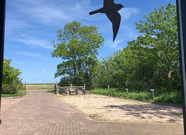 Holzschild mit der Aufschrift "Gaestehaus" an einem Ferienhaus in Oosterend, Texel, umgeben von Gruenanlagen.