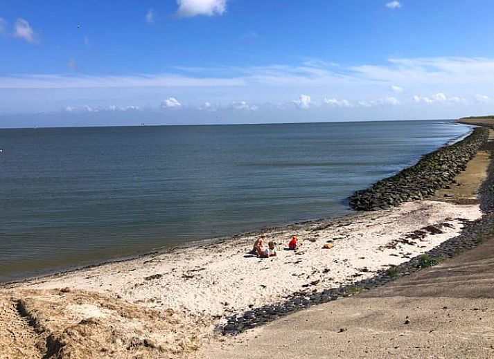 Gemuetlicher Innenbereich des Ferienhauses in Oosterend, Texel, mit Essbereich und offener Treppe.