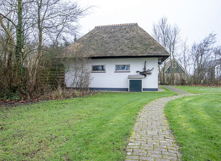 Gezellig vakantiehuis Nieuwlanderweg 69 met rieten dak in De Koog, Texel, omringd door groen en een ruim terras.