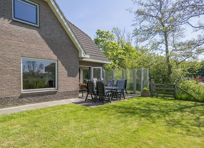 Dining area in vacation home Nieuwlanderweg 69, De Koog, Texel, with round table and garden view for cozy meals.
