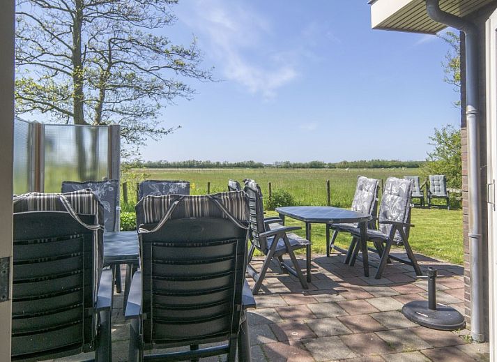 Dining area in vacation home Nieuwlanderweg 69, De Koog, Texel, with round table and garden view for cozy meals.