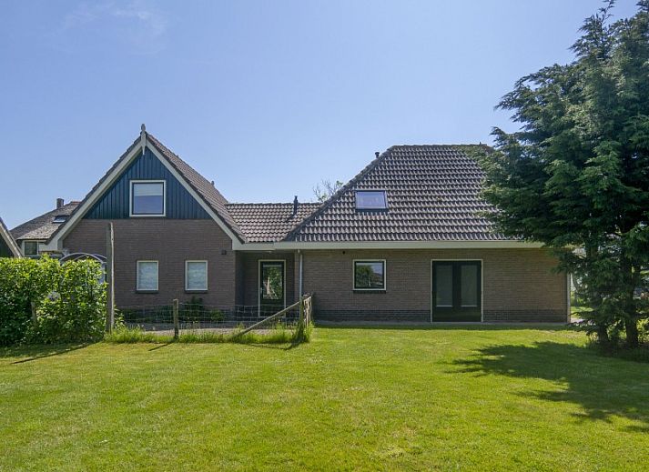 Open kitchen and living room in vacation home Nieuwlanderweg 69, De Koog, Texel, with wooden stairs and cozy furnishings.