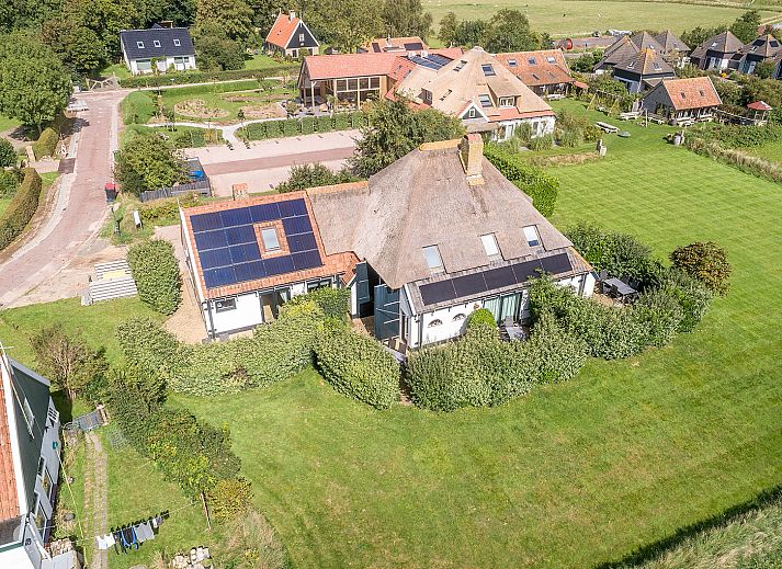 Lichte zithoek in Gouden Rijder vakantiehuis, Oosterend, Texel, met uitzicht op de tuin en moderne inrichting.