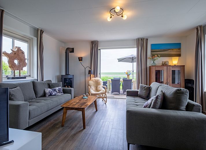 Terrasse von De Kokkel in Oosterend, Texel mit Gartenmoebeln und Sonnenschirm fuer ein entspanntes Leben im Freien.