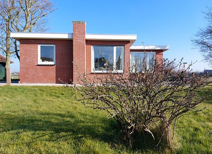 Frontansicht des Ferienhauses 't Buurtje in Oudeschild, Texel, umgeben von gruener Natur.