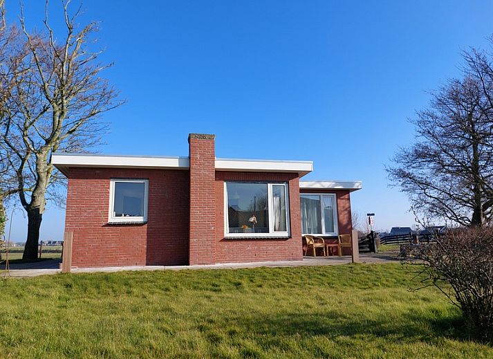 Frontansicht des Ferienhauses 't Buurtje in Oudeschild, Texel, umgeben von gruener Natur.