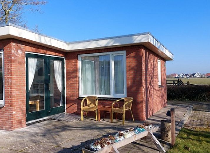 Frontansicht des Ferienhauses 't Buurtje in Oudeschild, Texel, umgeben von gruener Natur.