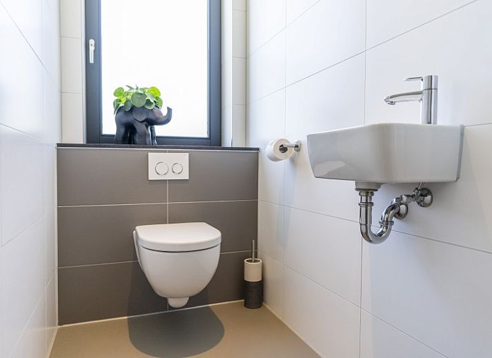 Innenraum von Rovershut - Familienhaus 1 in Dennenbos, Texel. Modernes Esszimmer im Ferienhaus mit grossem Esstisch und stilvoller Beleuchtung.