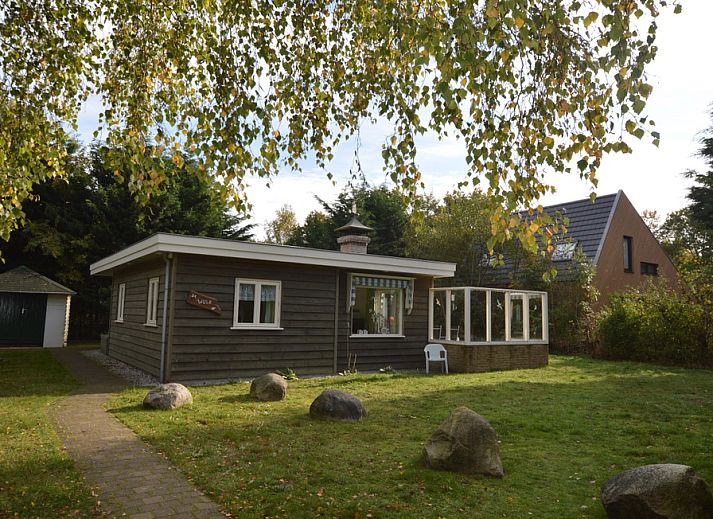 Buitenzijde van Vakantiehuis De Nagtegaal 15, De Wulk in De Dennen, Texel, omgeven door groene natuur.