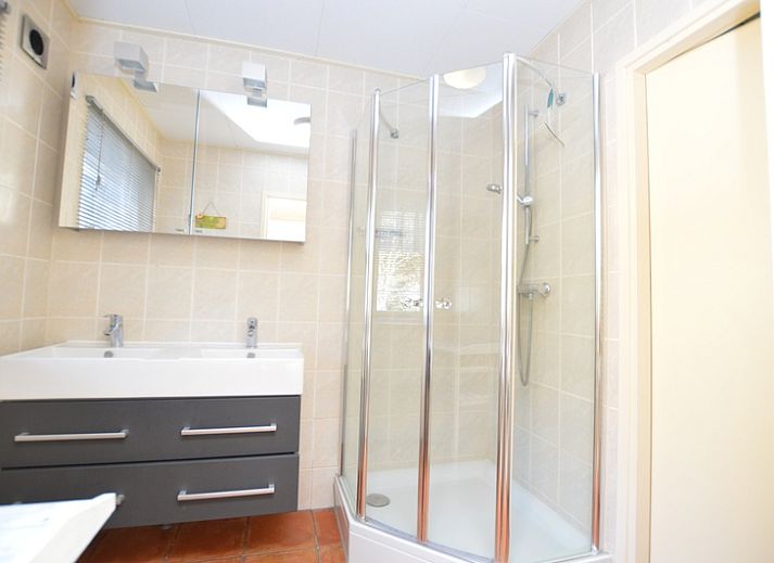 Gezellige woonkamer van Vakantiehuis De Nagtegaal 15, De Wulk in De Dennen, Texel met kleurrijke gordijnen.