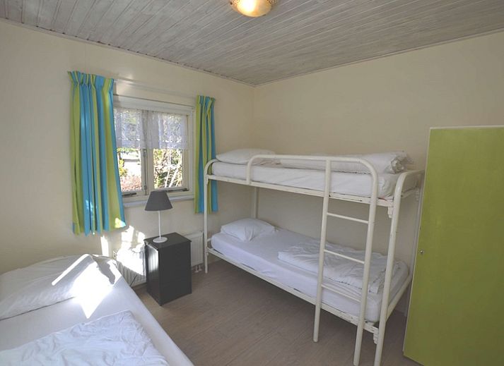 Gezellige woonkamer van Vakantiehuis De Nagtegaal 15, De Wulk in De Dennen, Texel met kleurrijke gordijnen.