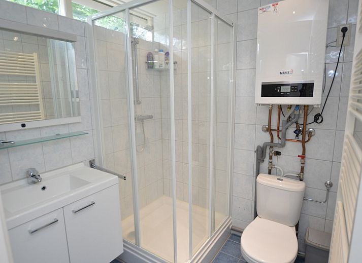 Lichte woonkamer van Vakantiehuis de Parel 182 in De Dennen, Texel met uitzicht op de tuin.