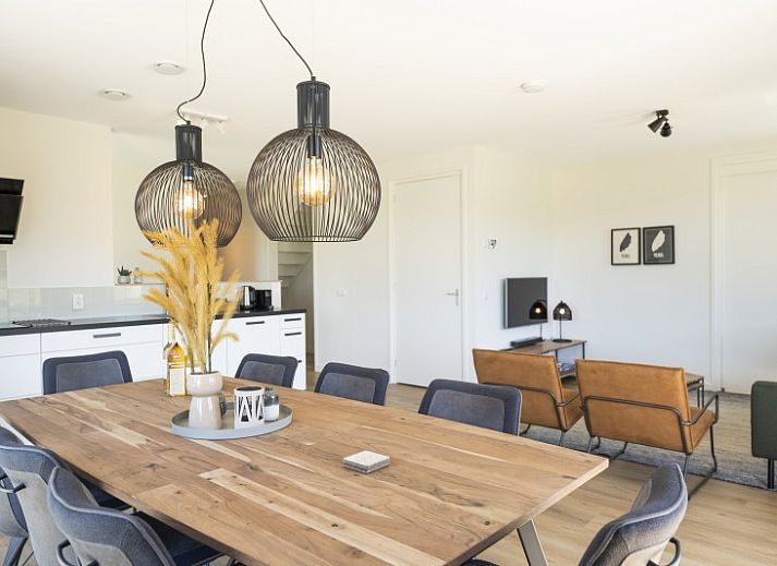 Terras van Rovershut - Familiehuis 2 in De Dennen, Texel, met comfortabele loungebank en weids uitzicht op de natuur.