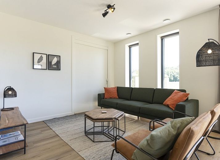 Terras van Rovershut - Familiehuis 2 in De Dennen, Texel, met comfortabele loungebank en weids uitzicht op de natuur.
