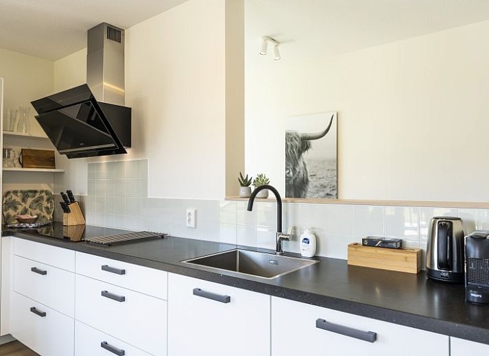 Terras van Rovershut - Familiehuis 2 in De Dennen, Texel, met comfortabele loungebank en weids uitzicht op de natuur.