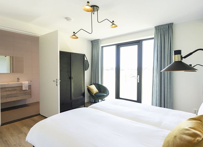 Buitenterras van Rovershut - Familiehuis 2 in De Dennen, Texel, met zithoek en eettafel onder een parasol.