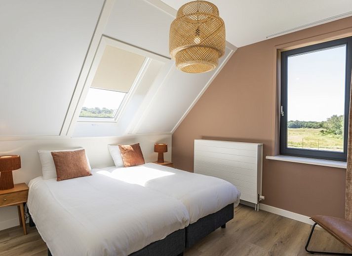 Buitenterras van Rovershut - Familiehuis 2 in De Dennen, Texel, met zithoek en eettafel onder een parasol.