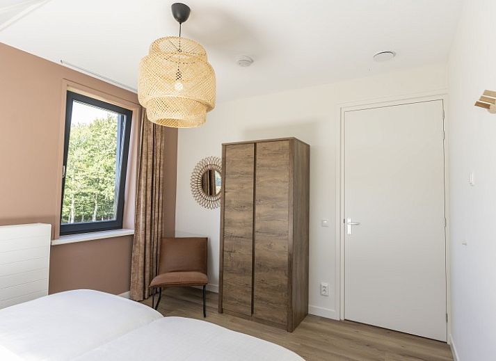 Buitenterras van Rovershut - Familiehuis 2 in De Dennen, Texel, met zithoek en eettafel onder een parasol.