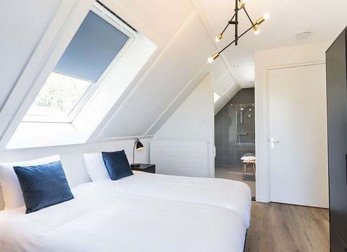 Kind speelt op trampoline voor Rovershut - Familiehuis 2 in De Dennen, Texel, met vakantiehuis op de achtergrond.