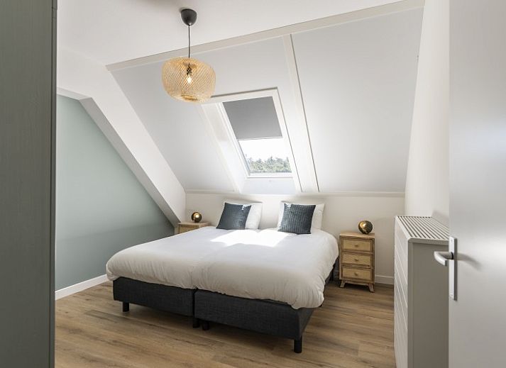 Kind speelt op trampoline voor Rovershut - Familiehuis 2 in De Dennen, Texel, met vakantiehuis op de achtergrond.