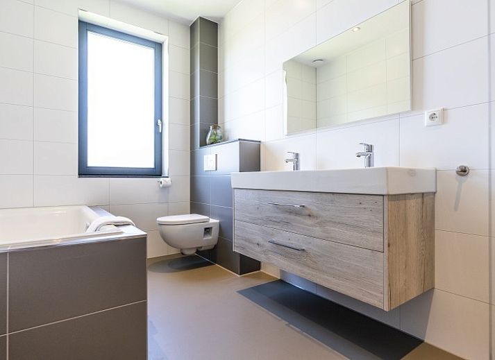 Kind speelt op trampoline voor Rovershut - Familiehuis 2 in De Dennen, Texel, met vakantiehuis op de achtergrond.